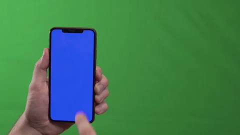 Studio shot of hand tapping phone against green backdrop for tutorials Stock Footage 324569088