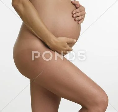 Studio shot of nude pregnant woman holding stomach Stock-Fotos