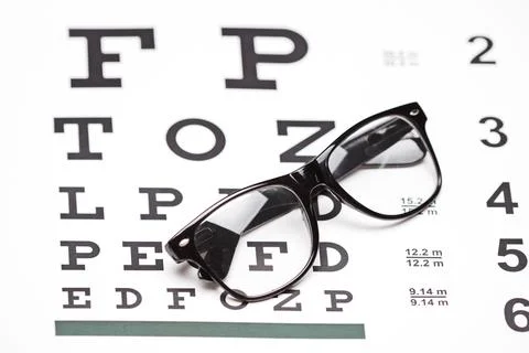 Studio shot of a pair of glasses on an eye chart on white background Stock Photos