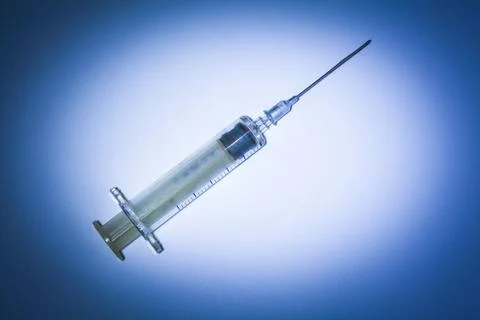 Studio shot of a plastic syringe with needle and plunger on a blue background Stock Photos