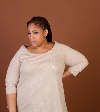 Studio shot of a plus size black woman in a beige top Stock Photos