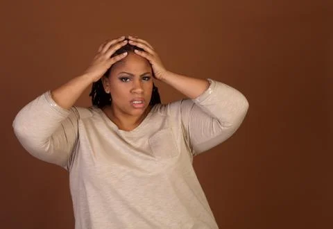 Studio shot of a plus size black woman in a beige top Stock Photos