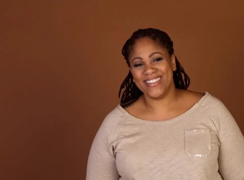 Studio shot of a plus size black woman in a beige top Stock Photos