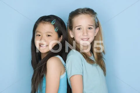 Studio shot portrait of two teenage girls standing back to back, head and Stock Photos