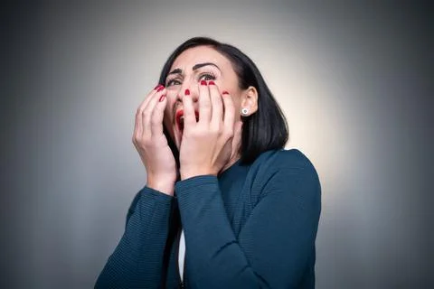 Studio shot of scared or afraid brunette female on grey background Foto stock