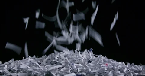 Studio shot of shredded paper falling into frame piling up on sleek black Video stock 123735738