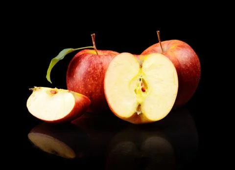 Studio shot of sliced red apple with leaf isolated on a black background Stock Photos
