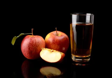 Studio shot of sliced red apple with leaf and apple juice isolated on a black Stock Photos