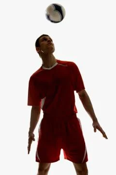 Studio shot of a soccer player bouncing a soccer ball on his head Stock Photos