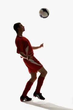 Studio shot of a soccer player bouncing a soccer ball on his chest Stock Photos