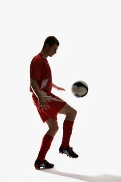 Studio shot of a soccer player bouncing a soccer ball on his knee Stock Photos