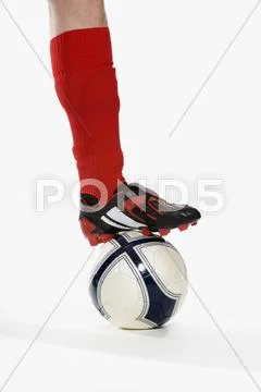 Studio shot of a soccer player's leg and his foot on top of a soccer ball Stock Photos