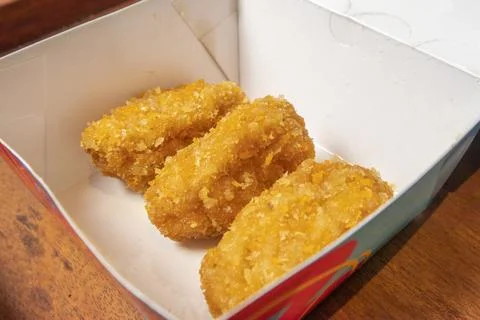 Studio shot of three breaded fried snacks inside an open paper box resting .. Fotos Stock