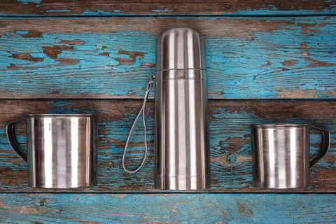 Studio shot of two metal cups and thermos flask on old blue wooden board Free Stock Photos