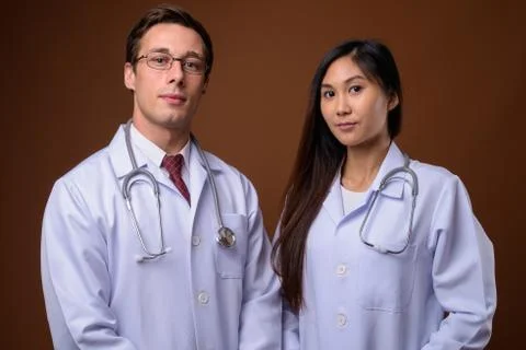 Studio shot of two young doctors together against brown backgrou 스톡 사진