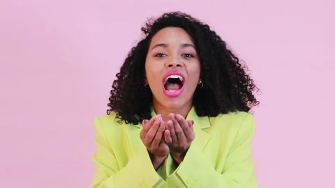 Studio shot of young afro-american women blowing confetti shape of heart on p Stock Footage 170203552