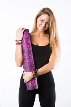 Studio shot of young beautiful blonde woman holding yoga mat and posing ready Stock Photos