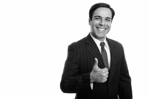 Studio shot of young happy Persian businessman smiling while giving thumb up Stock Photos