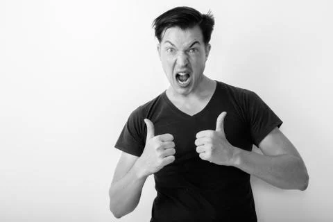 Studio shot of young man looking excited while giving thumbs up against white Stock Photos
