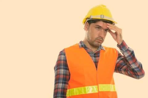Studio shot of young Persian man construction worker looking stressed Stock Photos