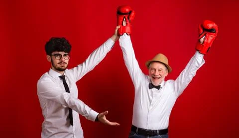 Studio shot of young versus old generation, a father and son with boxing glove. Stock Photos