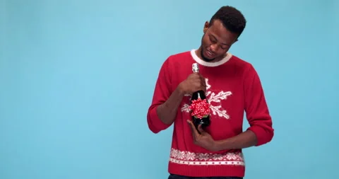 Studio, smiling young man in a Christmas sweater posing with a wine bottle Stock Footage 140425399