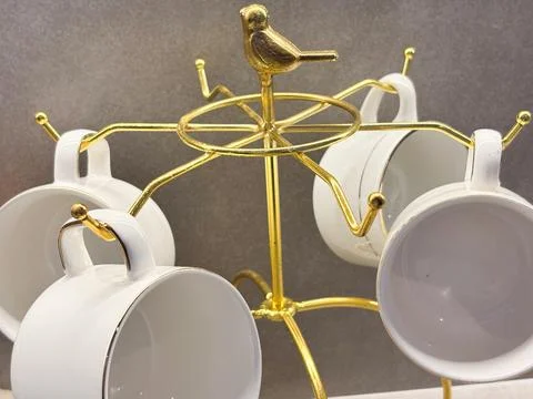 Studio-style shot of an elegant gold-toned metal mug or cup holding rack. Stock-Fotos