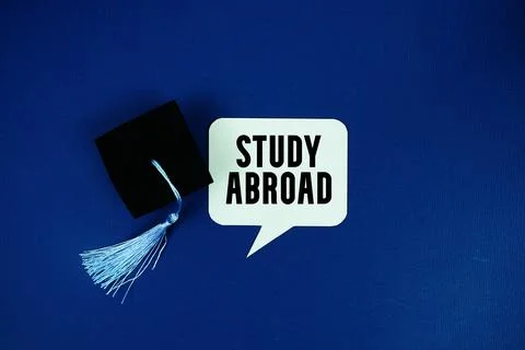 Study Abroad text on speech bubble with graduation cap top view on navy blu.. Stock Photos