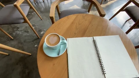 Study and work at the cafe. a cup coffee with an open book on the wooden table Stock Footage 218765991