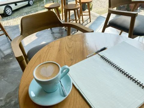 Study and work at the cafe. a cup coffee with an open book on the wooden table Stock Photos