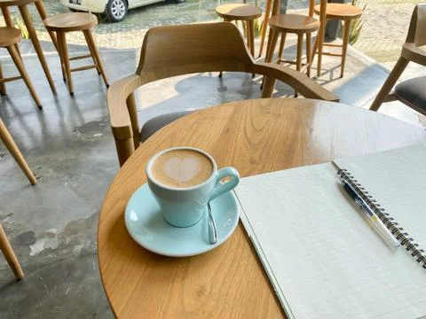 Study and work at the cafe. a cup coffee with an open book on the wooden table Stock Photos