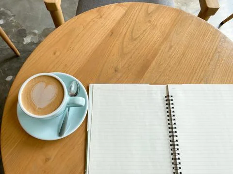 Study and work at the cafe. a cup coffee with an open book on the wooden table Stock Photos