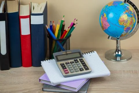 On a study desk, you will find a calculator, various notebooks, and a globe.. Stock Photos
