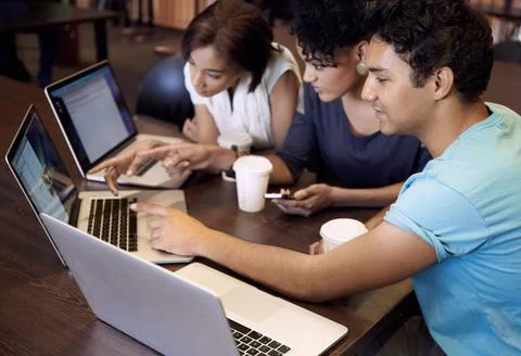 Study group dynamics. A group of students using a laptop to complete a group Stock Photos