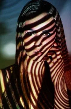 Study of light and beauty. Studio shot of a young woman with projected patterns Foto stock