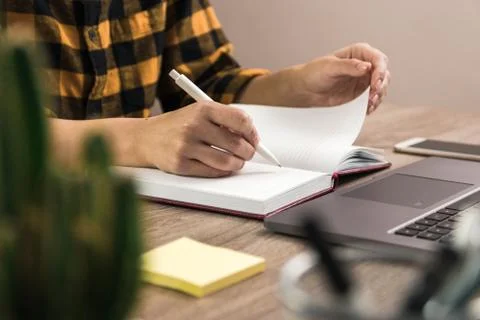 Study is power. close up hands of a student yellow shirt making notes Stock Photos