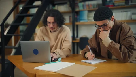 Study session in a library with students using laptops and notebooks Stock Footage 337165571