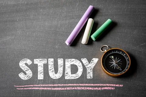 Study. Text, colored pieces of chalk and a compass on a chalkboard Stock Photos