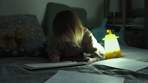 Studying and drawing in a complete darkness during electricity outage Stock Footage 229324859