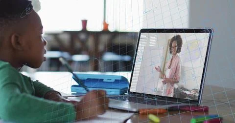 Studying boy in green top solving math in notebook at home, laptop showing Stock Photos