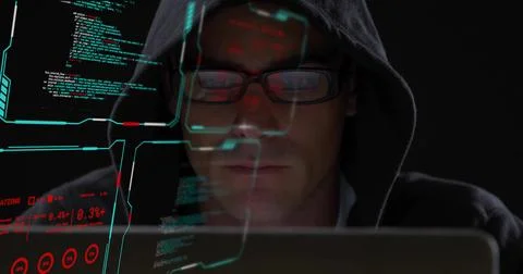 Studying coder in dark hoodie and glasses reading code on laptop in dark room, 스톡 사진