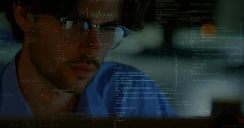 Studying developer focusing on code at dim workstation, wearing blue shirt, Stock Photos