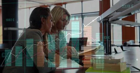 Studying documents, two women in blazer, patterned blouse at library with Stock Photos