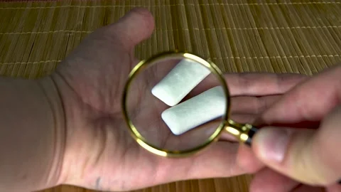 Studying gum under a large magnifying glass man with white hands two pads on a Stock Footage 131785601