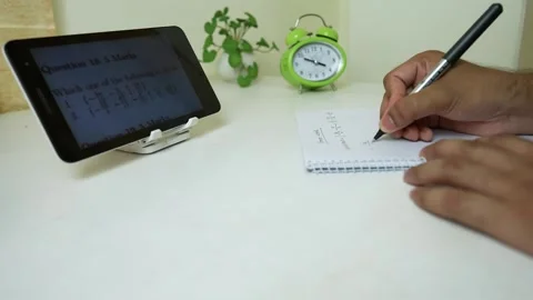 Studying with Tablet and Notes, Person taking notes from a tablet with a cl.. Stock Footage 318057289