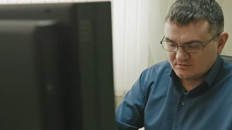 Stuff in office: man in glasses working at computer, close up Stock Footage 68044752