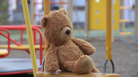 Stuffed Bear sits on a Childrens Swing. Toy Bear swings on a Swing Stock Footage 154046211
