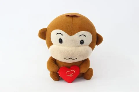 Stuffed brown monkey holding a red heart on a white background. 스톡 사진