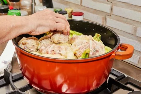 Stuffed cabbage rolls and stuffed tomatoes are cooked in saucepan on gas stov Stock-Fotos