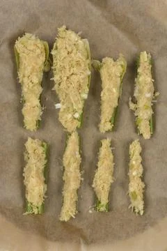 Stuffed celery stalks on baking paper top view Stock Photos